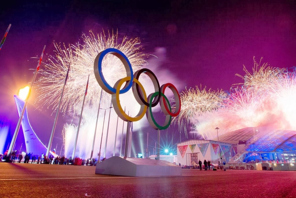 Winter Olympics 桌布 壁紙 — 奧運五環在夜間被照亮，壯觀的煙火在體育場和火炬上方爆炸。