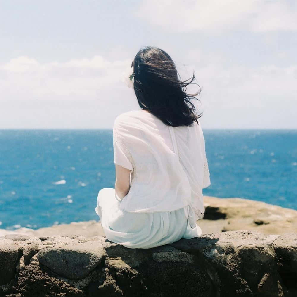 女子坐在岩石上眺望海洋 壁紙