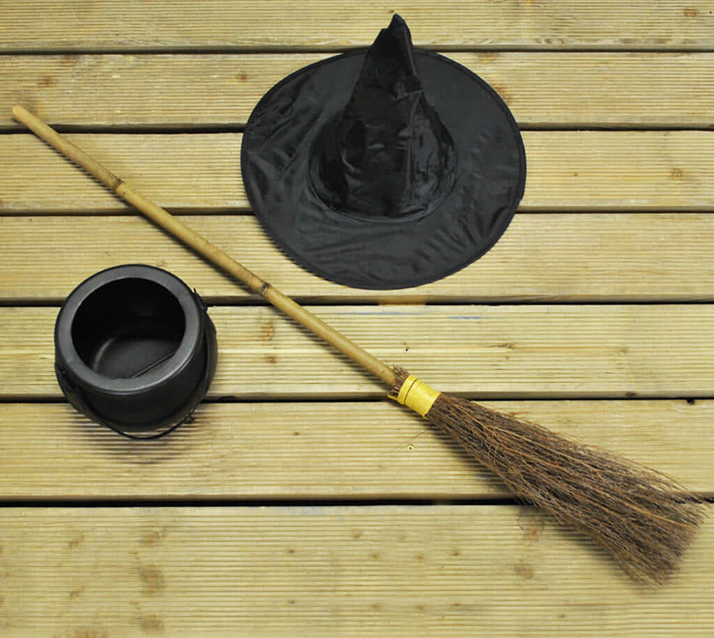 Witches Broom 桌布 壁紙 — 女巫帽、掃帚和大鍋放在風化的木板上，以平鋪構圖呈現。
