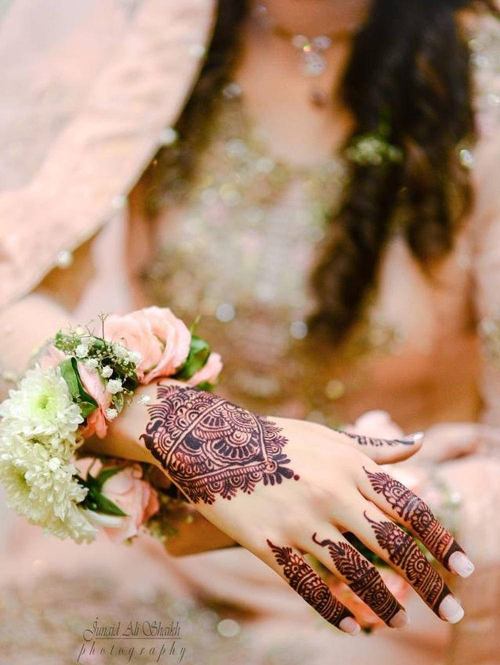 Bridal 桌布 壁紙 — 女性手部特寫，飾有複雜的深紅色指甲花圖案，手持粉紅色和白色花束。