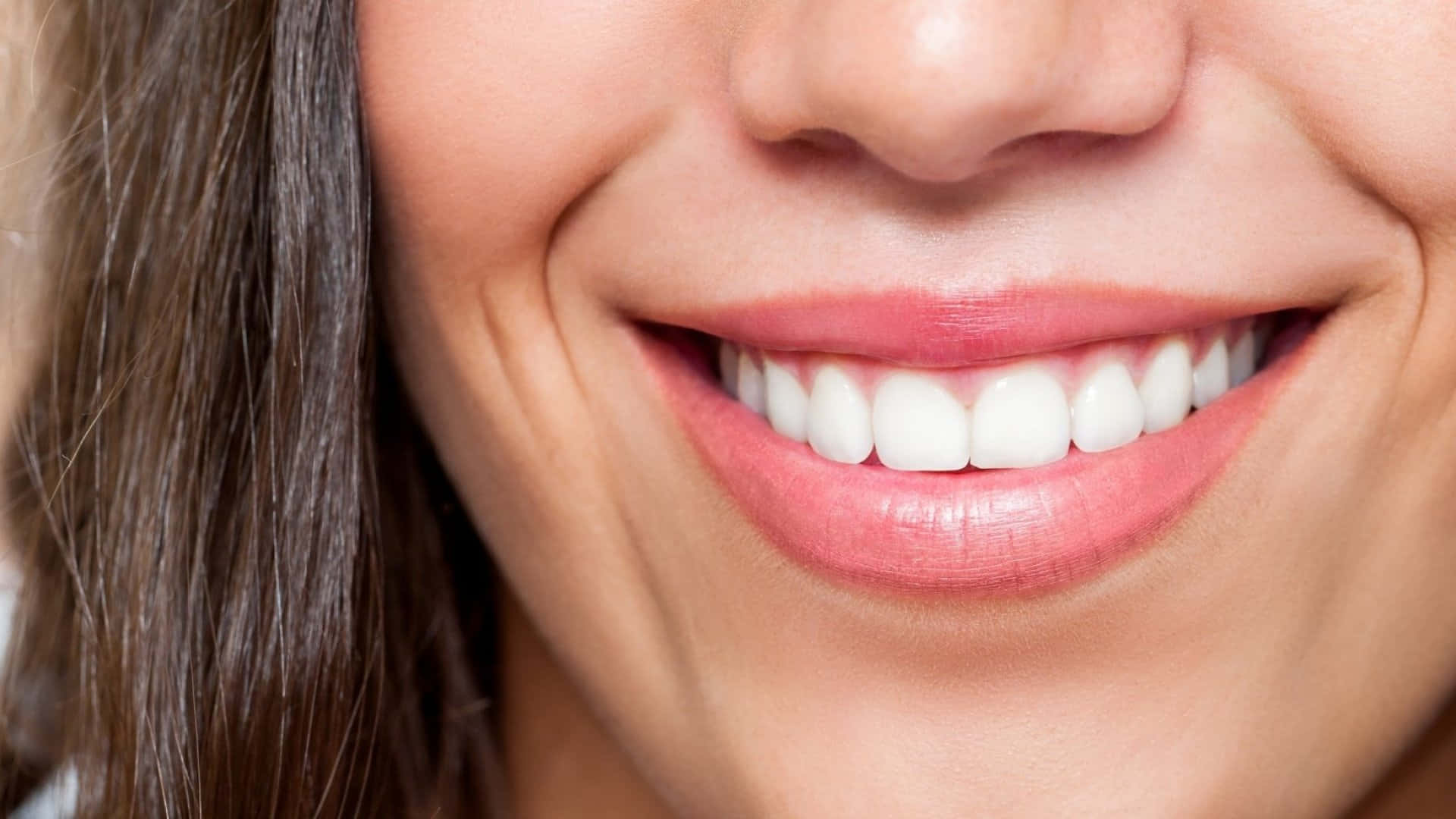 Smile 桌布 壁紙 — 女性燦爛笑容的特寫，展現完美的白色牙齒和柔軟的粉紅色嘴唇，棕色頭髮勾勒側面。