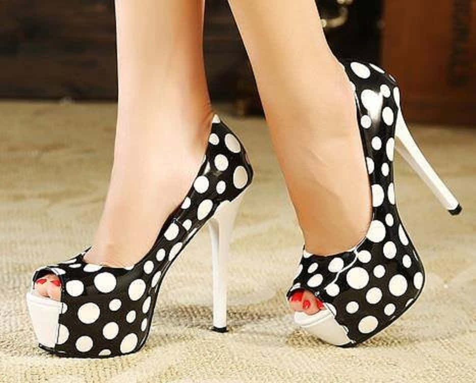 Footwear Design 桌布 壁紙 — 女性雙腳的特寫，穿著黑白圓點露趾厚底高跟鞋，紅色腳趾甲，站在有紋理的米色地毯上。