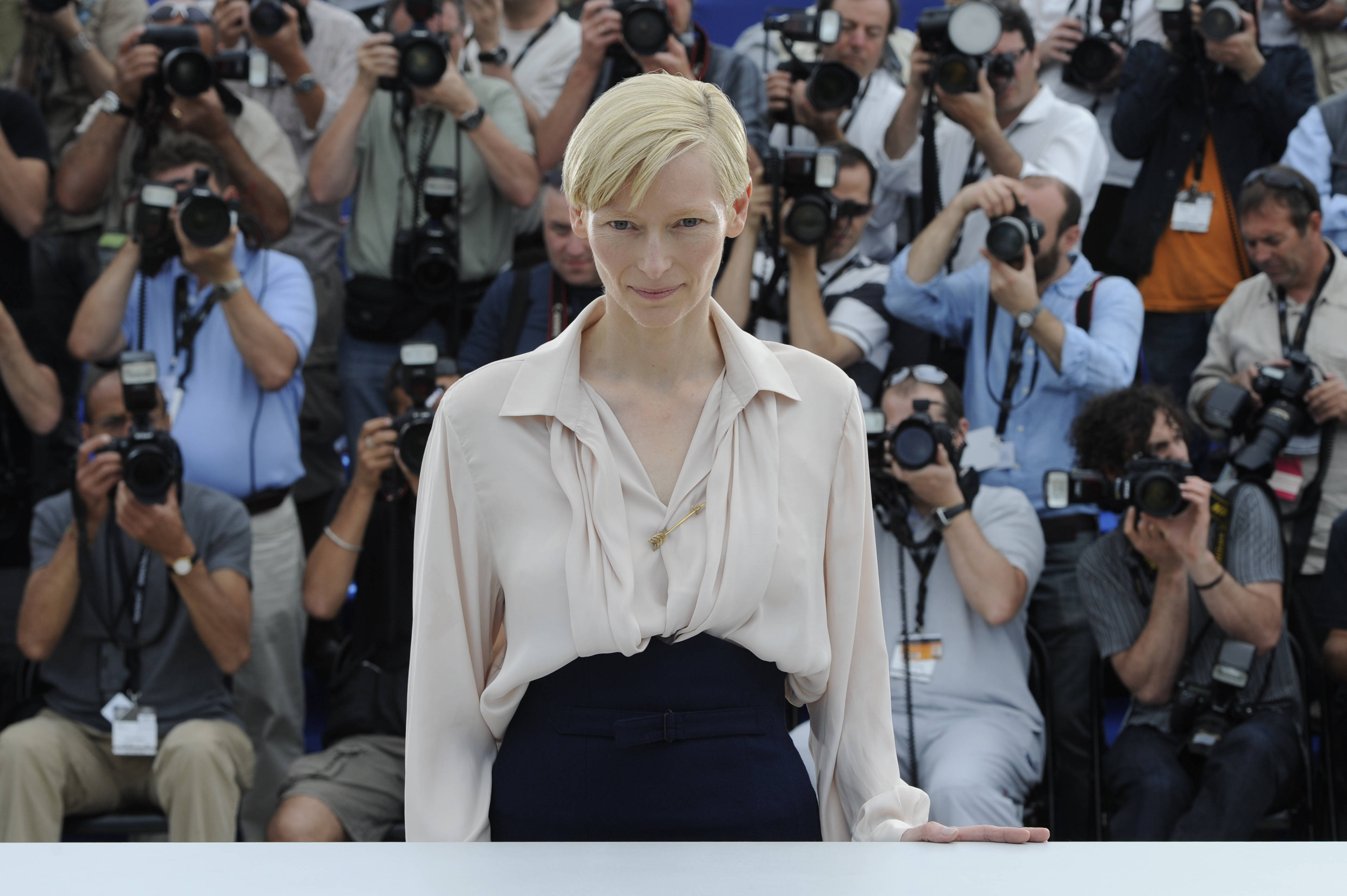 Celebrity 桌布 壁紙 — 女演員蒂妲·史雲頓在記者會上冷靜地站著，被拿著相機的攝影師包圍。