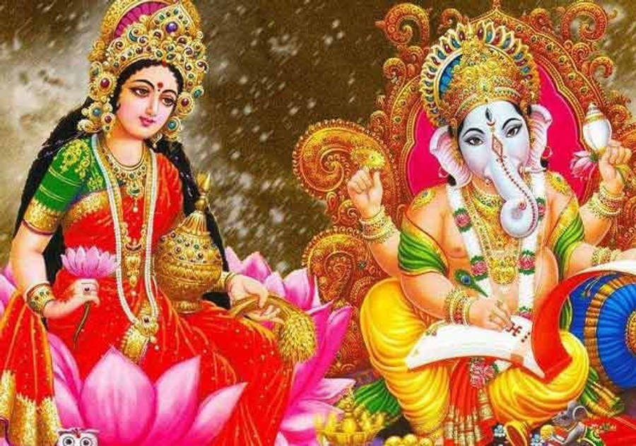 Lakshmi 桌布 壁紙 — 女神拉克什米和象神甘尼許佩戴著鮮豔的珠寶和色彩繽紛的服飾，莊嚴地坐在金色背景前的蓮花上。