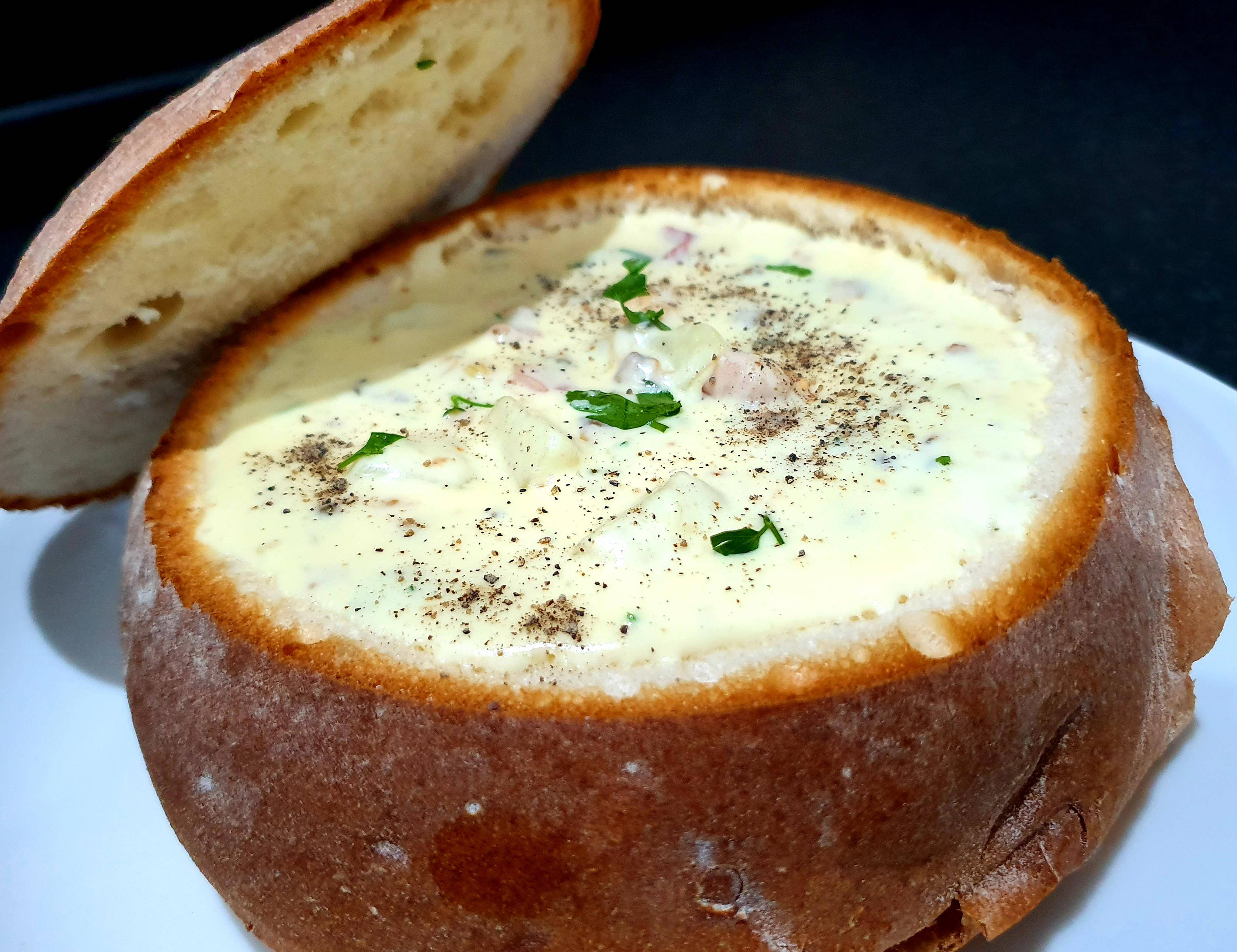 Chowder 桌布 壁紙 — 奶油湯盛載於挖空的麵包碗中，飾以新鮮香草和黑胡椒。