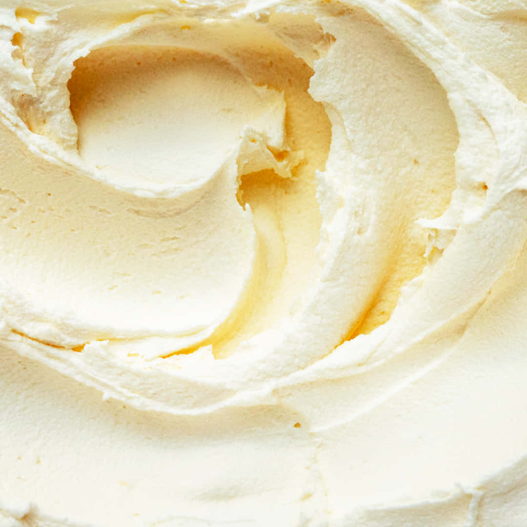 Buttercream 桌布 壁紙 — 奶油白色糖霜的特寫，帶有柔和漩渦和細微黃色底色。