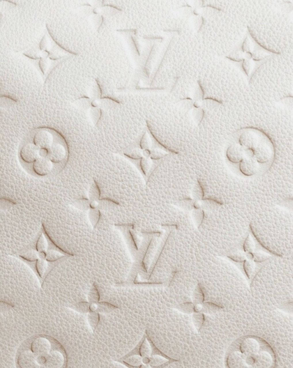 路易威登 桌布 壁紙 — 奶油白色紋理皮革的特寫，帶有壓花 Louis Vuitton 字母組合和花卉圖案。