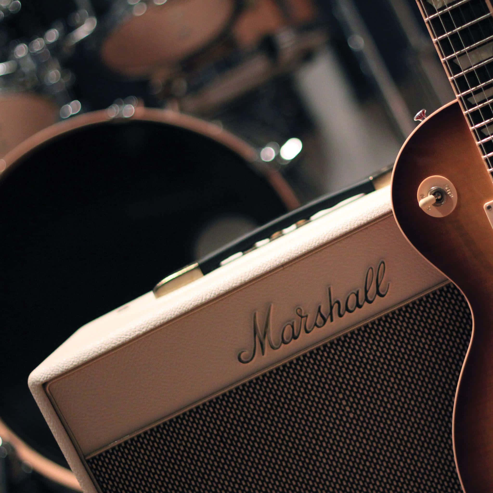 Marshall 桌布 壁紙 — 奶油色 Marshall 吉他擴大機的特寫，旁邊是一把 sunburst 電吉他，背景有鼓模糊。