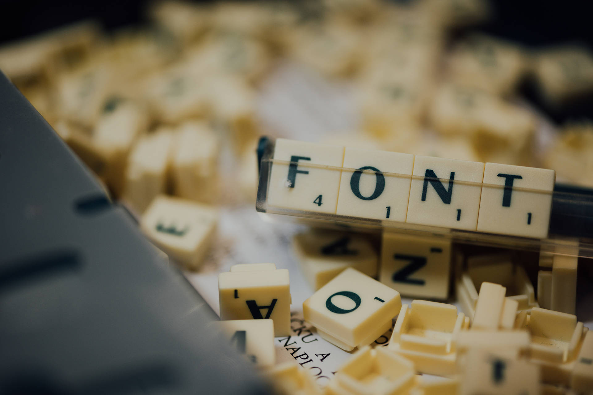桌上 Scrabble 字母塊拼出 FONT，附近有鍵盤。 — 字型 GIF 壁紙