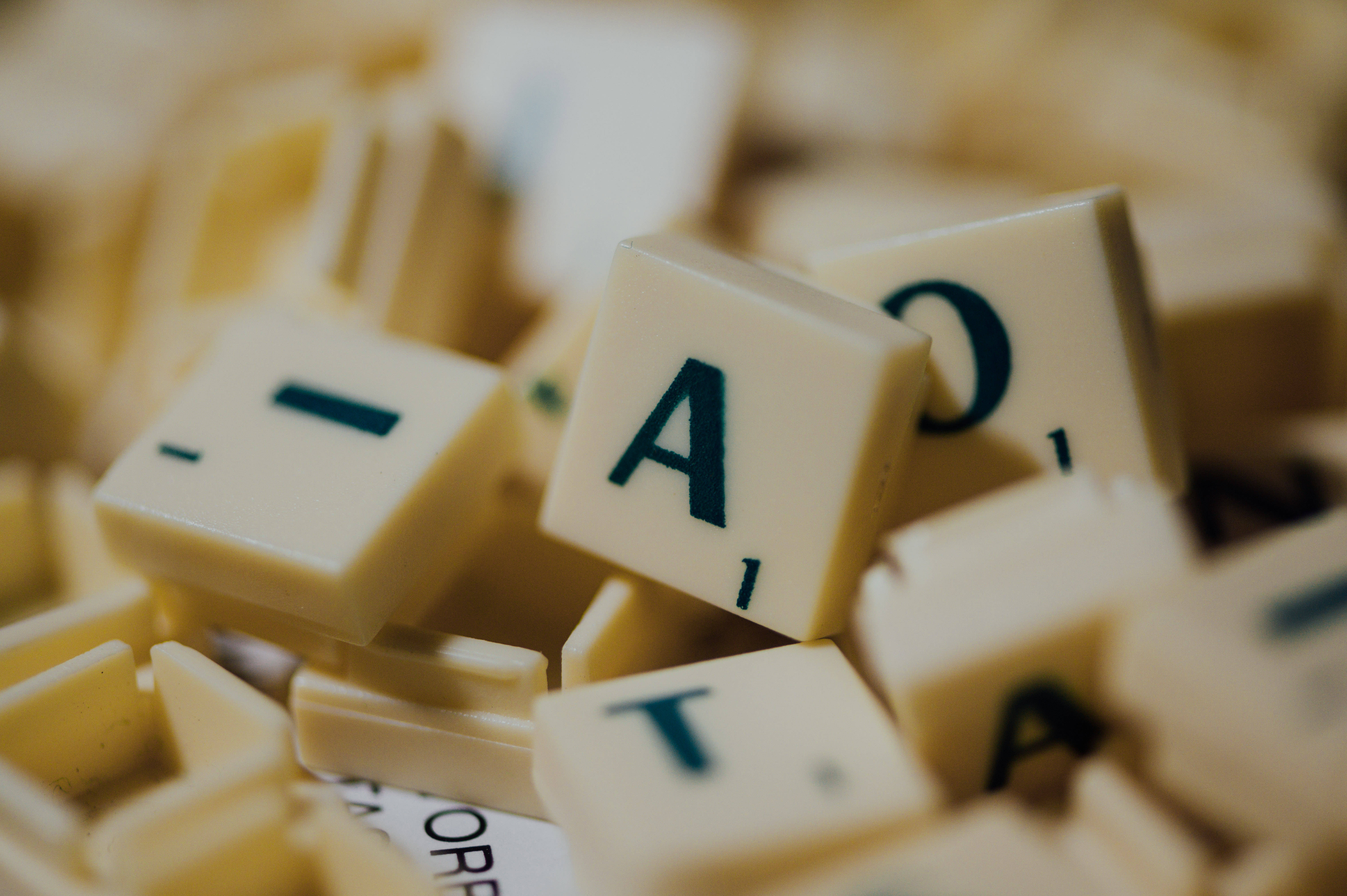 字型 桌布 壁紙 — 奶油色 Scrabble 字牌的特寫，深藍色字母散落在柔焦中。