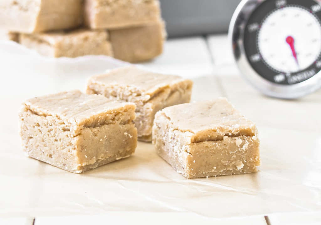 Penuche Fudge 桌布 壁紙 — 奶油花生醬軟糖方塊放在烘焙紙上，旁邊有一個廚房溫度計。