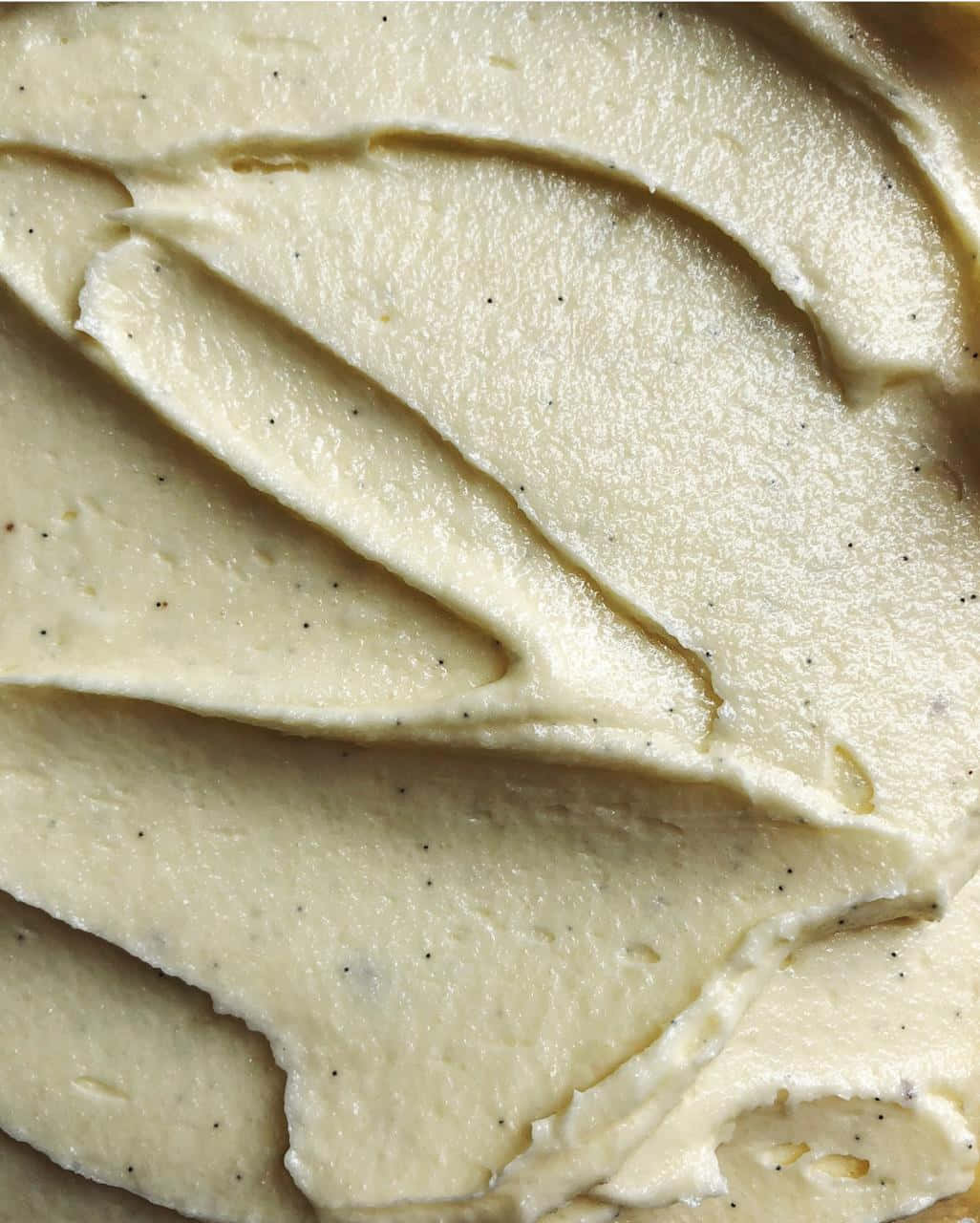 Buttercream 桌布 壁紙 — 奶油香草豆糖霜的特寫，帶有精緻的漩渦和斑點種子。