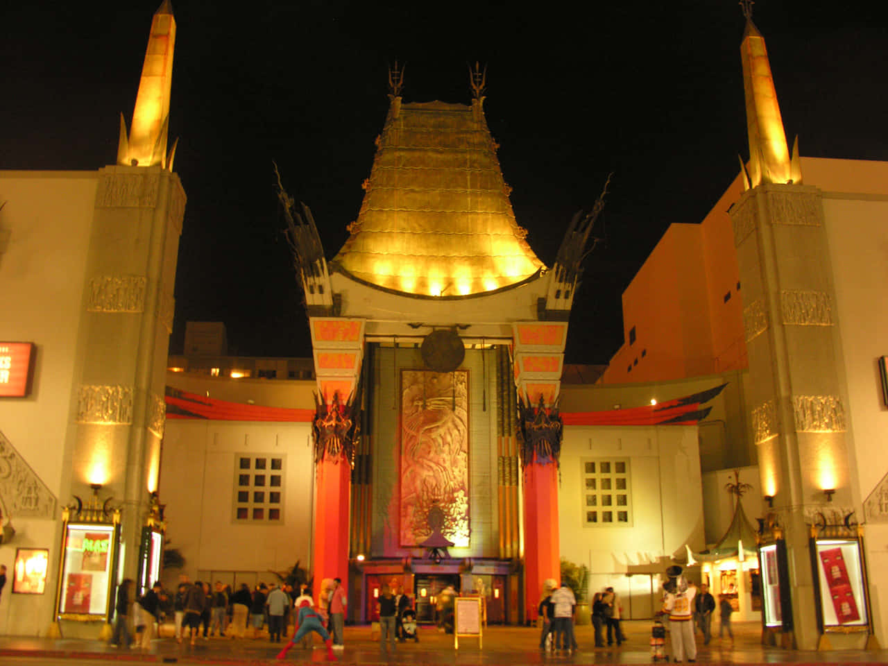 hollywood street 桌布 壁紙 — 好萊塢劇院大入口在夜間被金色燈光和紅色橫幅照亮，人群聚集在外面。