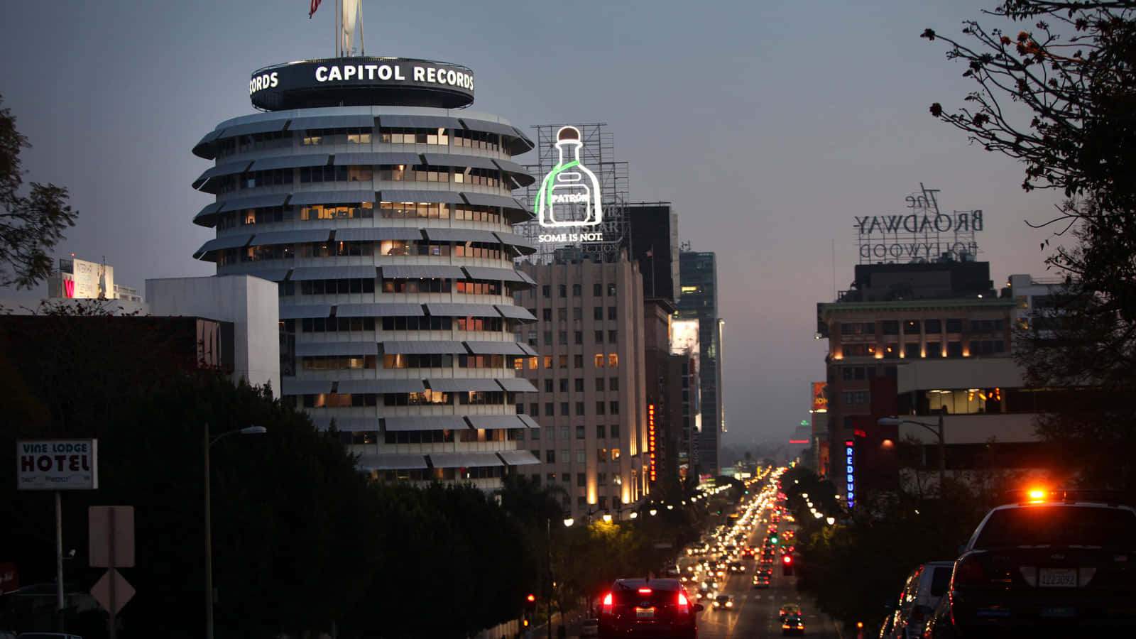 View 桌布 壁紙 — 好萊塢的黃昏，Capitol Records 大樓亮起燈光，車流沿著一條佈滿標誌性招牌的繁華街道流動。