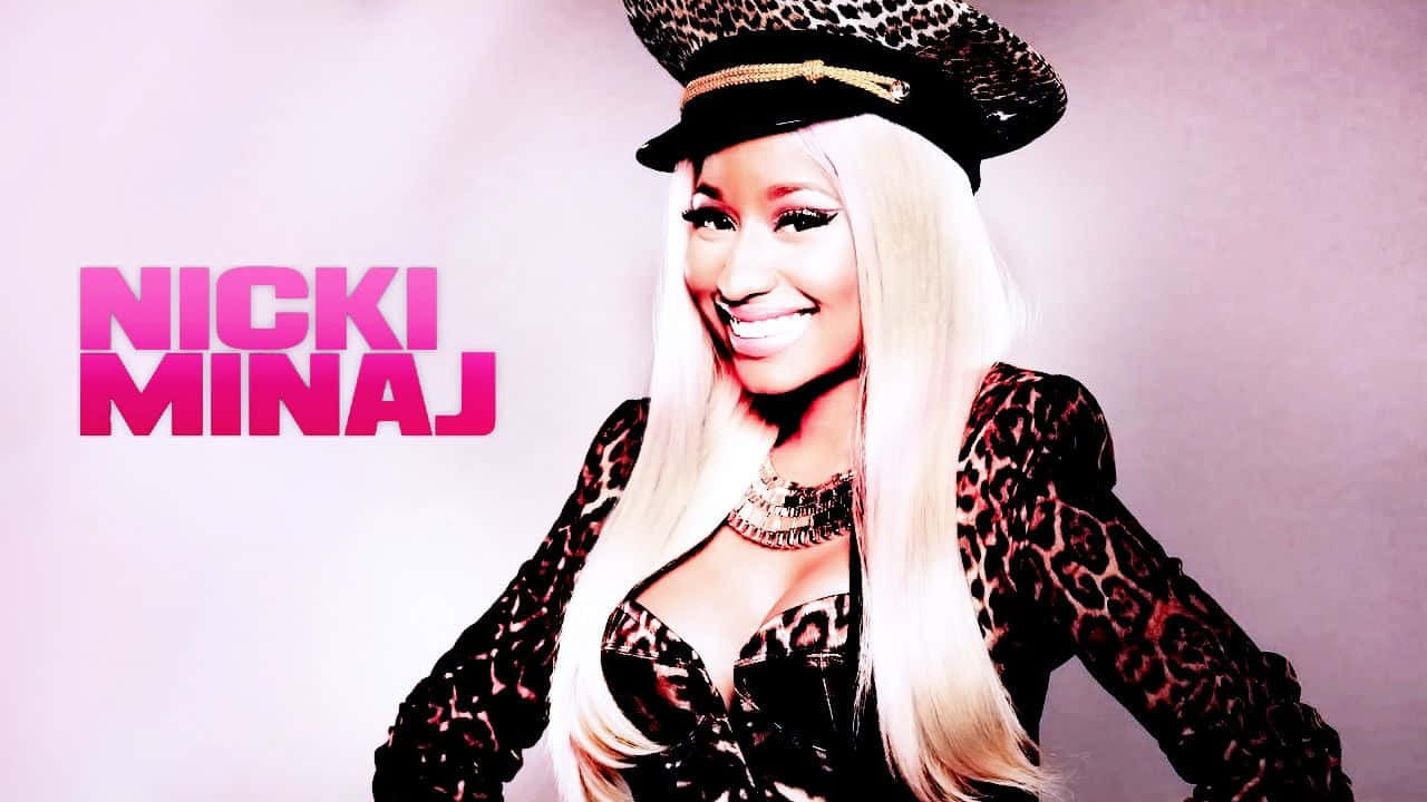 妮琪·米娜 桌布 壁紙 — 妮琪·米娜（Nicki Minaj）身穿豹紋套裝和帽子，在柔和的粉紅色背景前自信地微笑，她的名字以粗體粉紅色文字呈現。