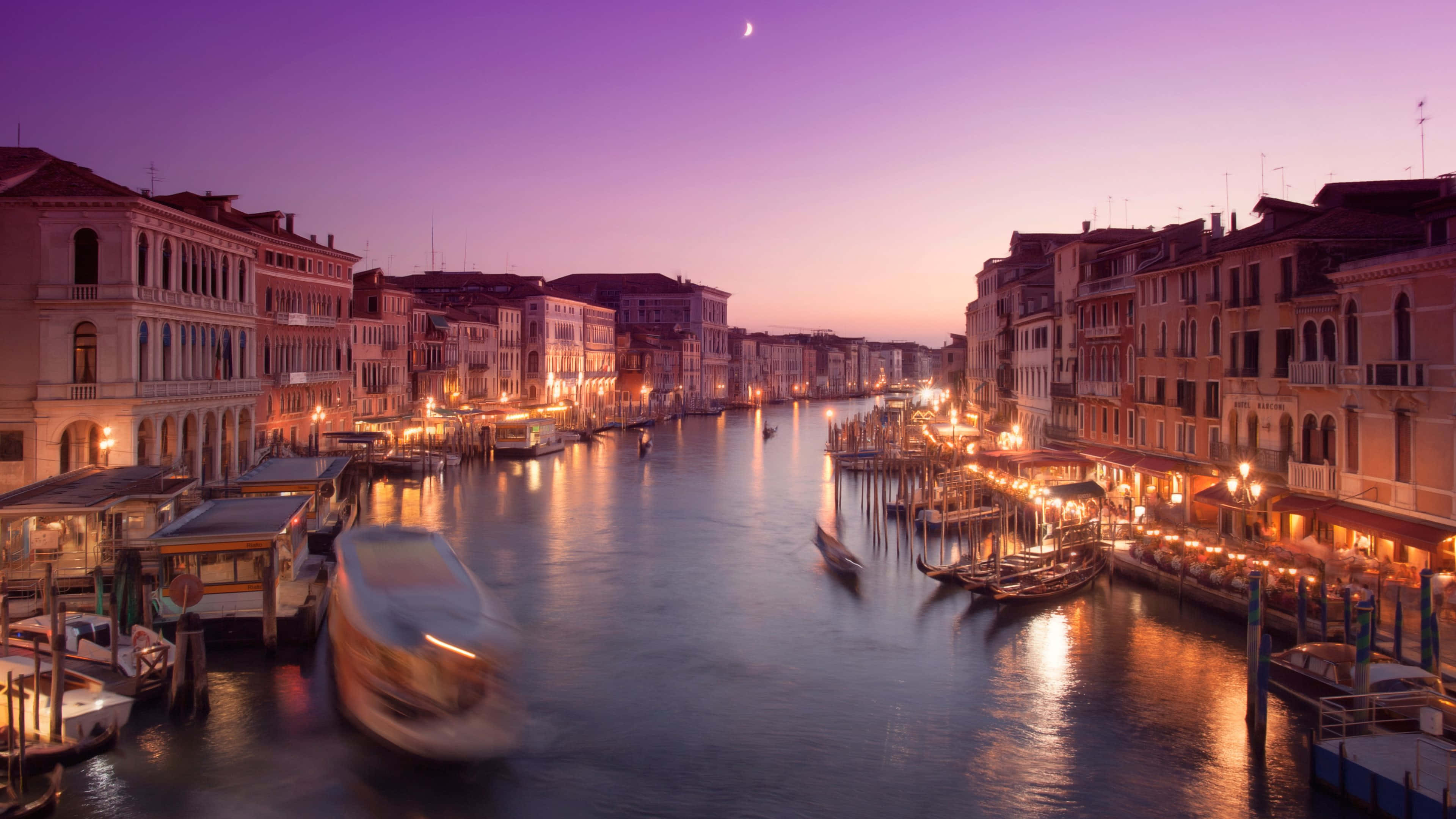 Italian 桌布 壁紙 — 威尼斯運河在黃昏時分，燈光在水面上閃爍，歷史建築上方掛著一彎新月。