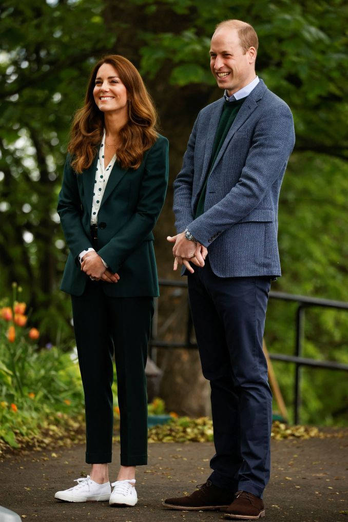 Kate Middleton 桌布 壁紙 — 威廉王子與凱特·米德爾頓在戶外一個綠意盎然、開滿橙色花朵的花園中溫暖微笑。