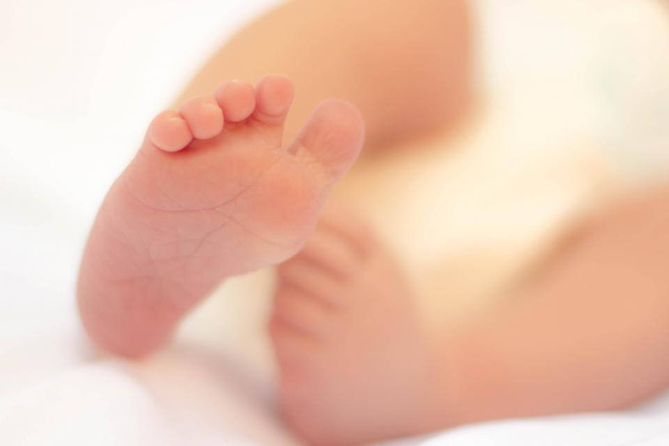 Very Cute Baby 桌布 壁紙 — 嬰兒小腳的特寫，擱在柔軟的白色布料上，背景有模糊的四肢。