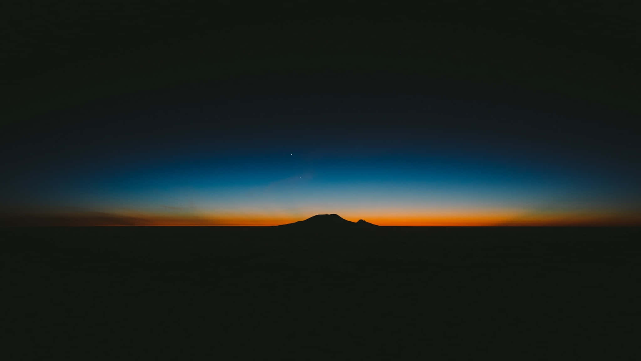 Horizon 桌布 壁紙 — 孤獨的山巒剪影矗立在漸變的暮色天空中，散發著深藍和火熱的橙色色調。