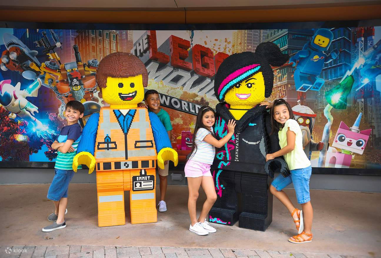 小孩動圖 桌布 壁紙 — 孩子們在充滿活力的LEGO主題景點中，與巨大的LEGO Emmet和Wyldstyle雕像愉快地合影。