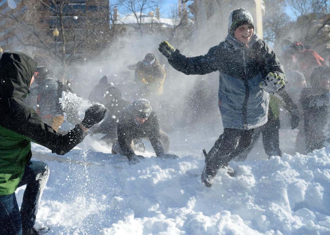 Snowball Fight 桌布 壁紙 — 孩子們在明亮的冬日裏開心地打雪仗，雪花在空中飛舞。