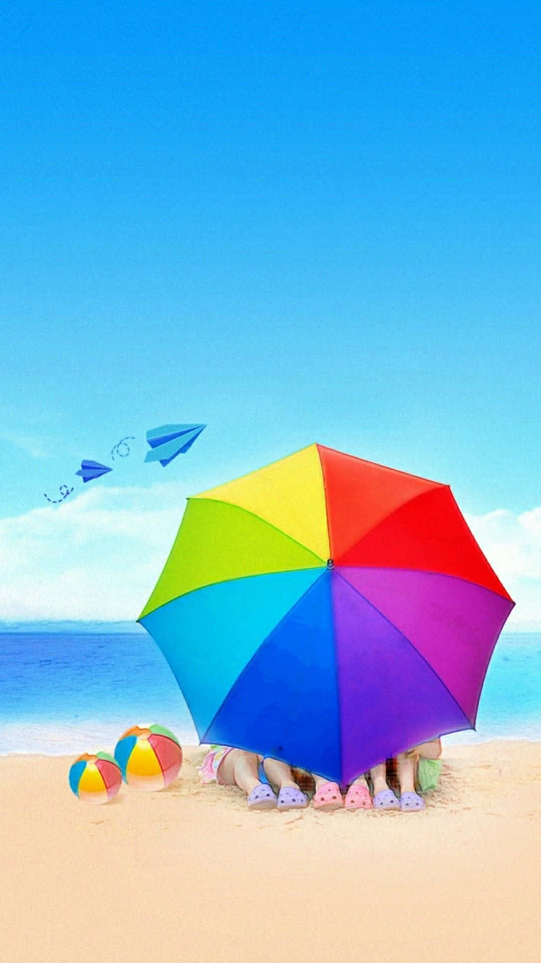Beach Umbrella 桌布 壁紙 — 孩子們在陽光明媚的海灘上從彩虹傘下探出頭來，紙飛機在頭頂飛翔。