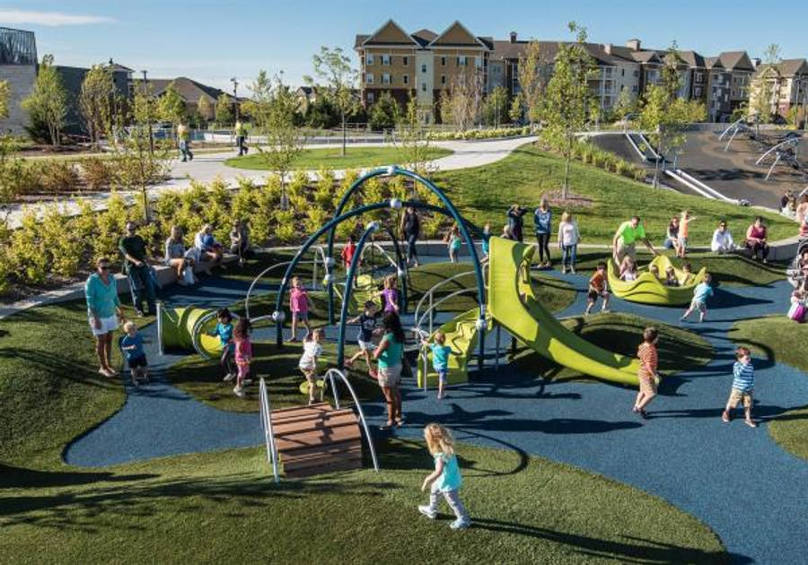 Minneapolis 桌布 壁紙 — 孩子們在陽光明媚的郊區遊樂場玩鮮綠色溜滑梯和攀爬設施，家長在附近觀看。