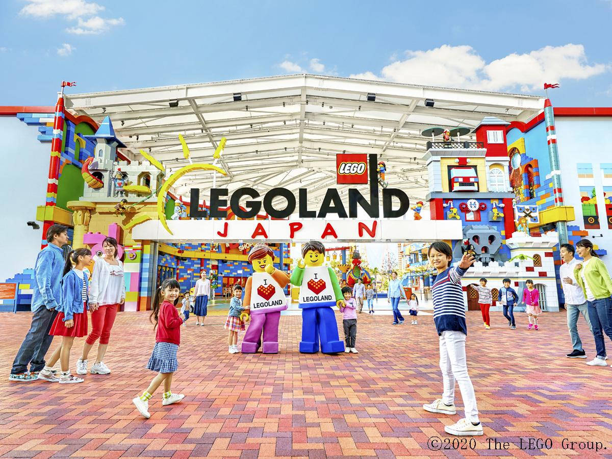 小孩動圖 桌布 壁紙 — 孩子和家庭在晴朗的藍天下，在 LEGOLAND Japan 色彩繽紛的 LEGO 主題入口前歡樂地擺姿勢。