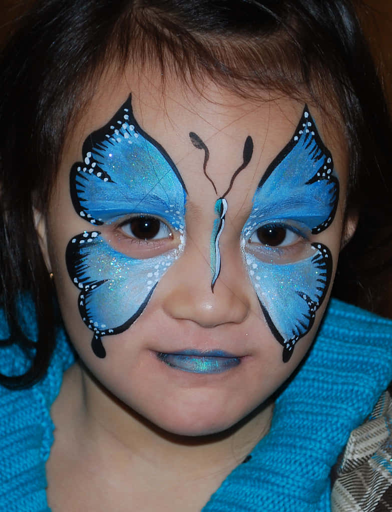 Butterfly Face Painting 桌布 壁紙 — 孩子的臉上繪有鮮豔的藍色蝴蝶翅膀和閃亮裝飾，營造節日氣氛。