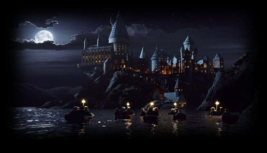 Hogwarts Castle 桌布 壁紙 — 學生們在船上提著燈籠，在黑暗的水面上滑行，朝著滿月下溫暖窗戶照亮的宏偉城堡前進。