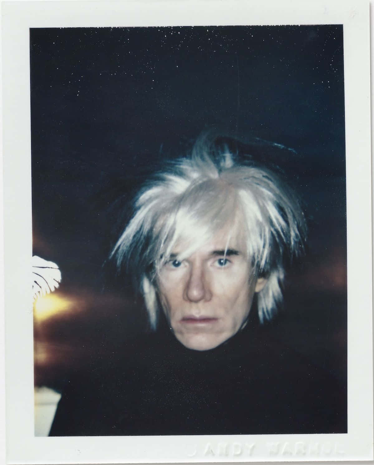 andy warhol 桌布 壁紙 — 安迪·沃荷的拍立得肖像，一頭凌亂的白髮，眼神銳利，背景是黑暗的星空。