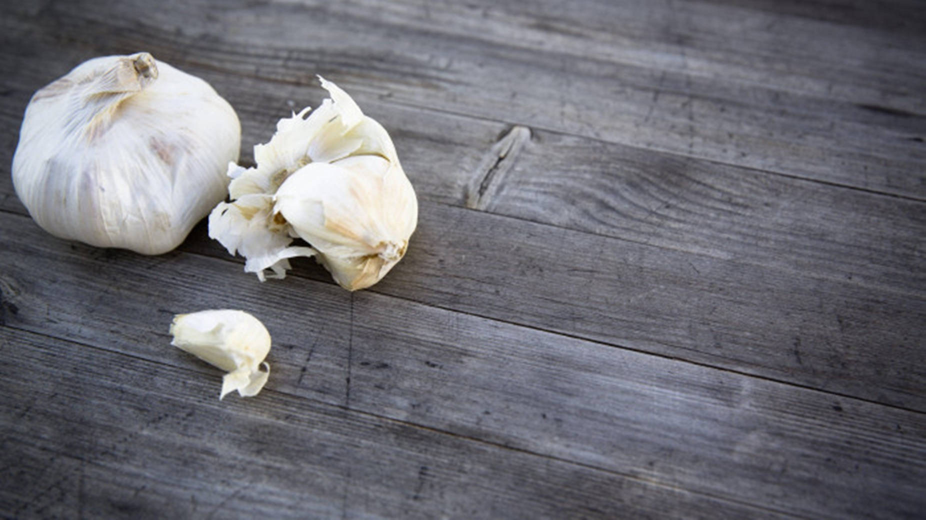 Garlic 桌布 壁紙 — 完整和去皮的蒜瓣放在一塊帶有天然木紋紋理的風化灰色木質表面上。