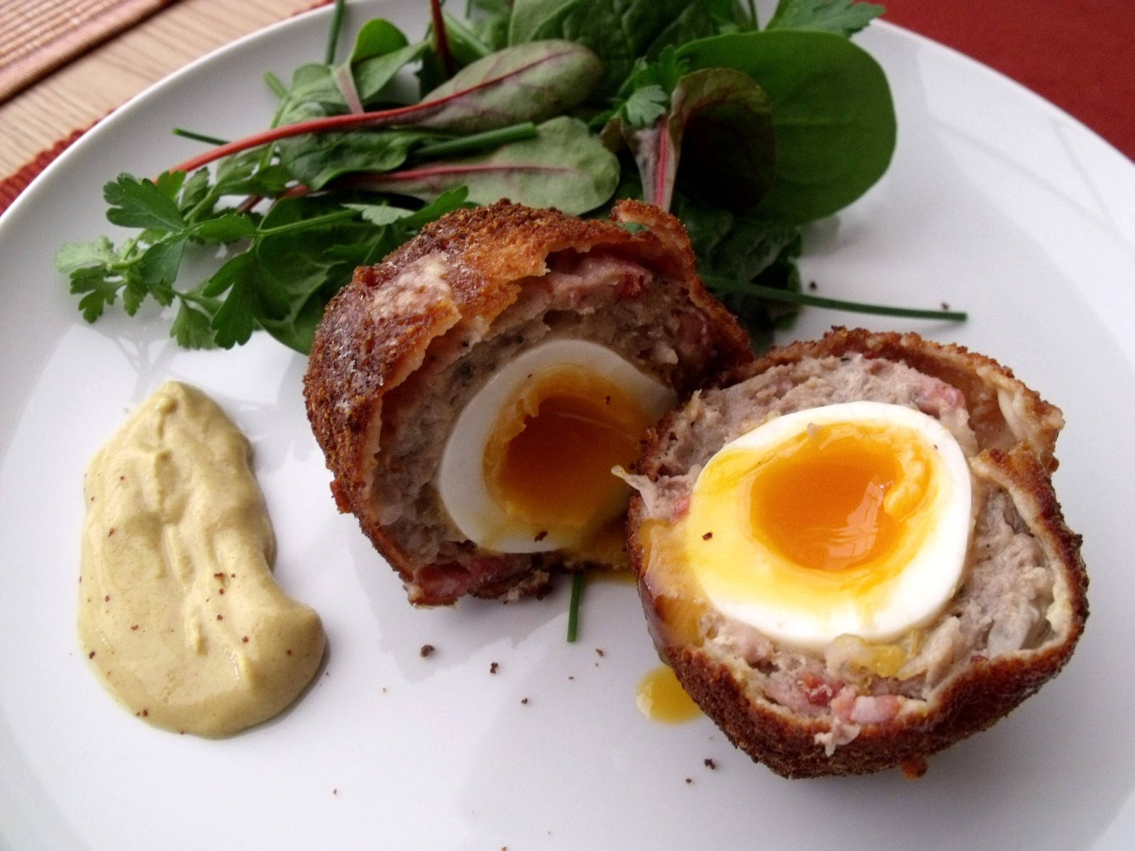 Egg 桌布 壁紙 — 完美切開的蘇格蘭蛋，流心蛋黃和酥脆外皮，配上新鮮蔬菜和芥末，盛載於白色盤子上。