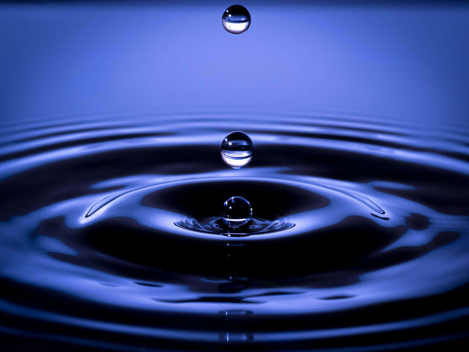 Water Drop 桌布 壁紙 — 完美捕捉深藍色液體中懸浮並泛起漣漪的水滴慢動作畫面。