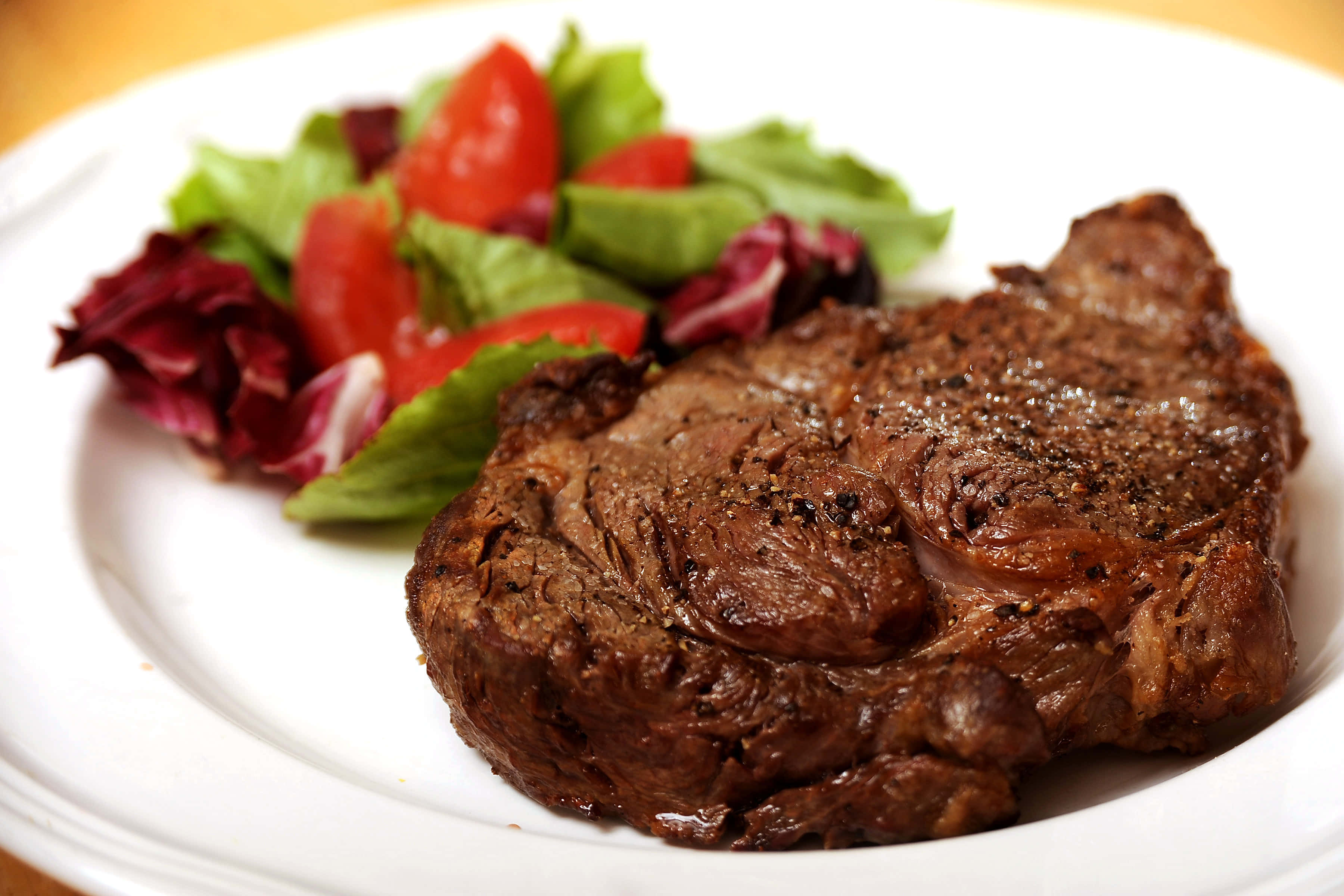 meat 桌布 壁紙 — 完美煎烤的牛排，外皮酥脆，搭配新鮮沙拉，盛於白色餐盤上。