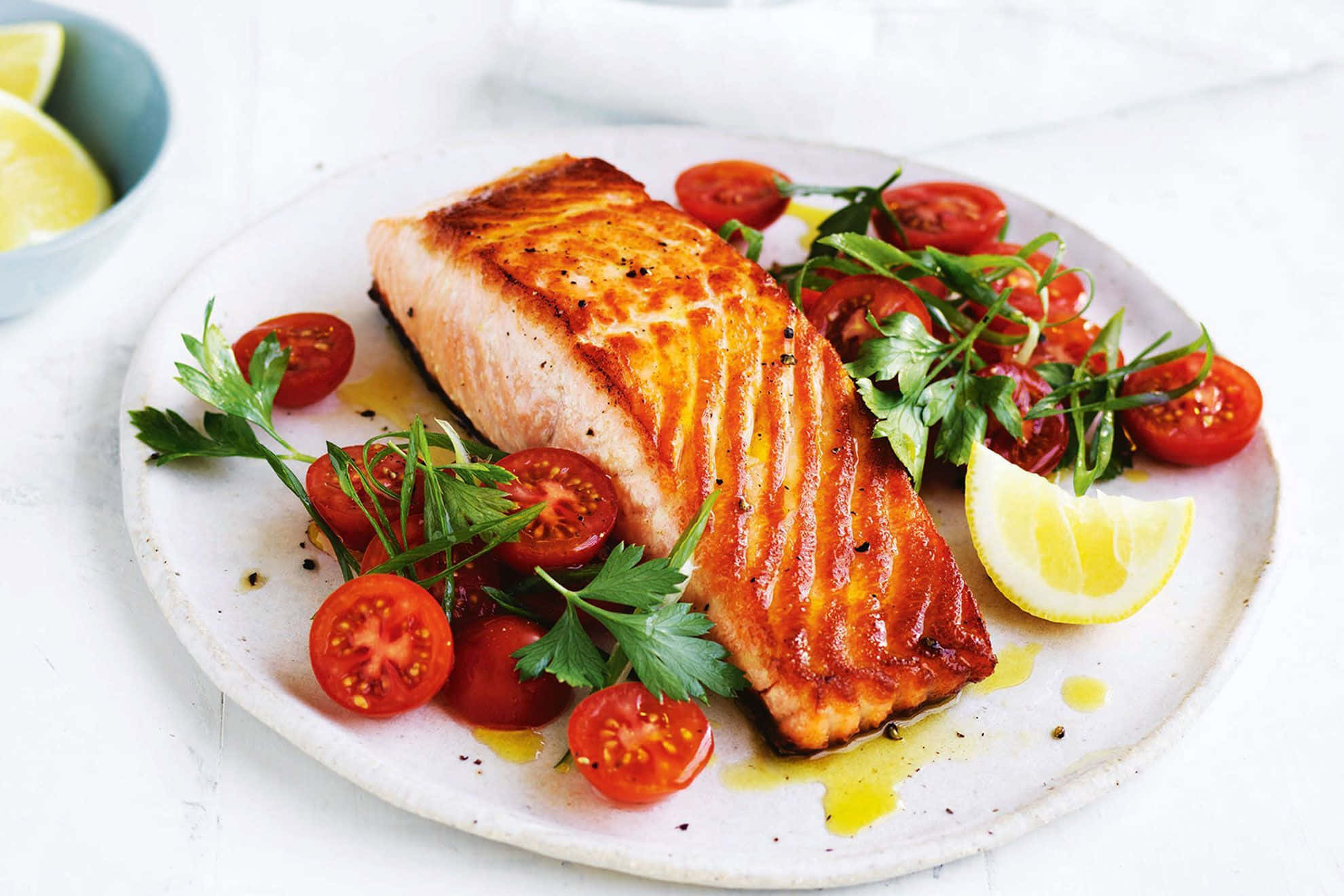 Salmon 桌布 壁紙 — 完美煎烤的鮭魚菲力放在盤子上，搭配櫻桃番茄、芝麻葉和檸檬角。