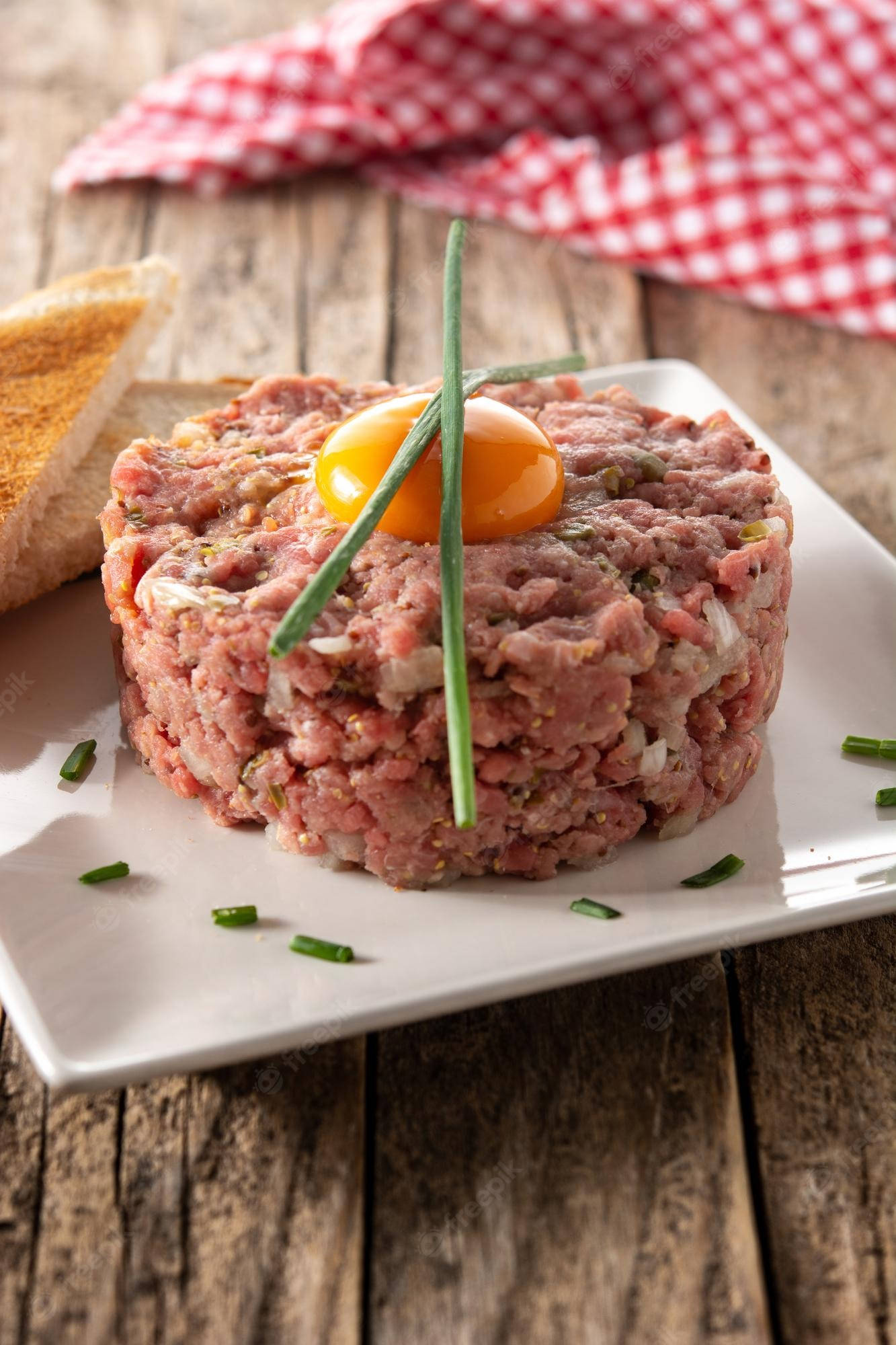 meat 桌布 壁紙 — 完美製作的牛肉他他，上面放有生蛋黃和細香蔥，置於鄉村風木桌上。