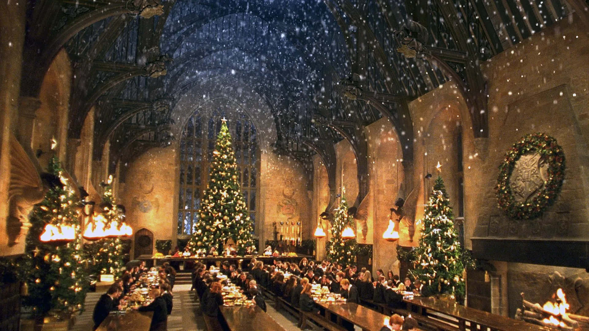 Harry Potter Christmas 桌布 壁紙 — 宏偉城堡的宴會廳，學生們在飄雪魔法天花板下、聳立聖誕樹旁用餐。