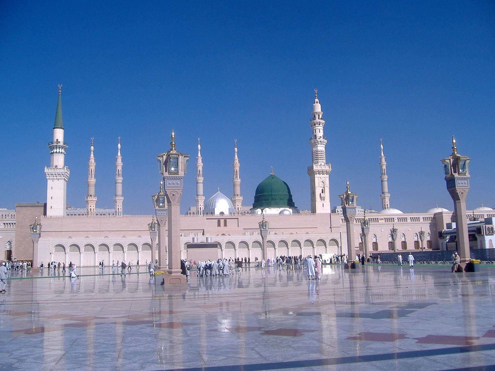 Makkah 桌布 壁紙 — 宏偉清真寺，綠色圓頂和宣禮塔，在清澈藍天下，倒映在拋光大理石廣場上，有禮拜者。
