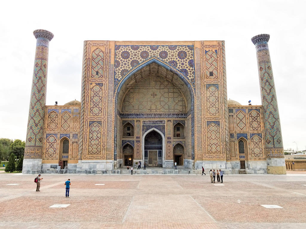 Uzbekistan 桌布 壁紙 — 宏偉的伊斯蘭建築傑作，擁有精緻的藍色和金色瓷磚工藝，兩側是高聳的宣禮塔，天空多雲。