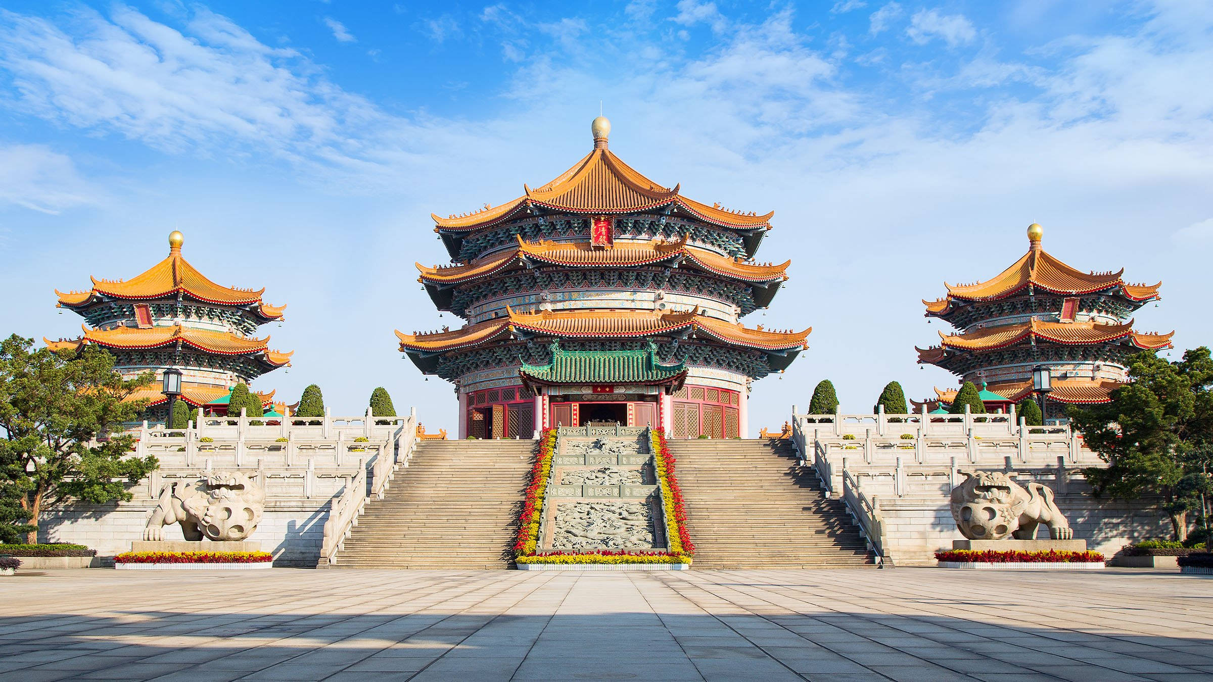 Guangzhou 桌布 壁紙 — 宏偉的傳統中國寺廟建築群，擁有層疊的橙色屋頂和石獅雕像，在明亮的藍天下。