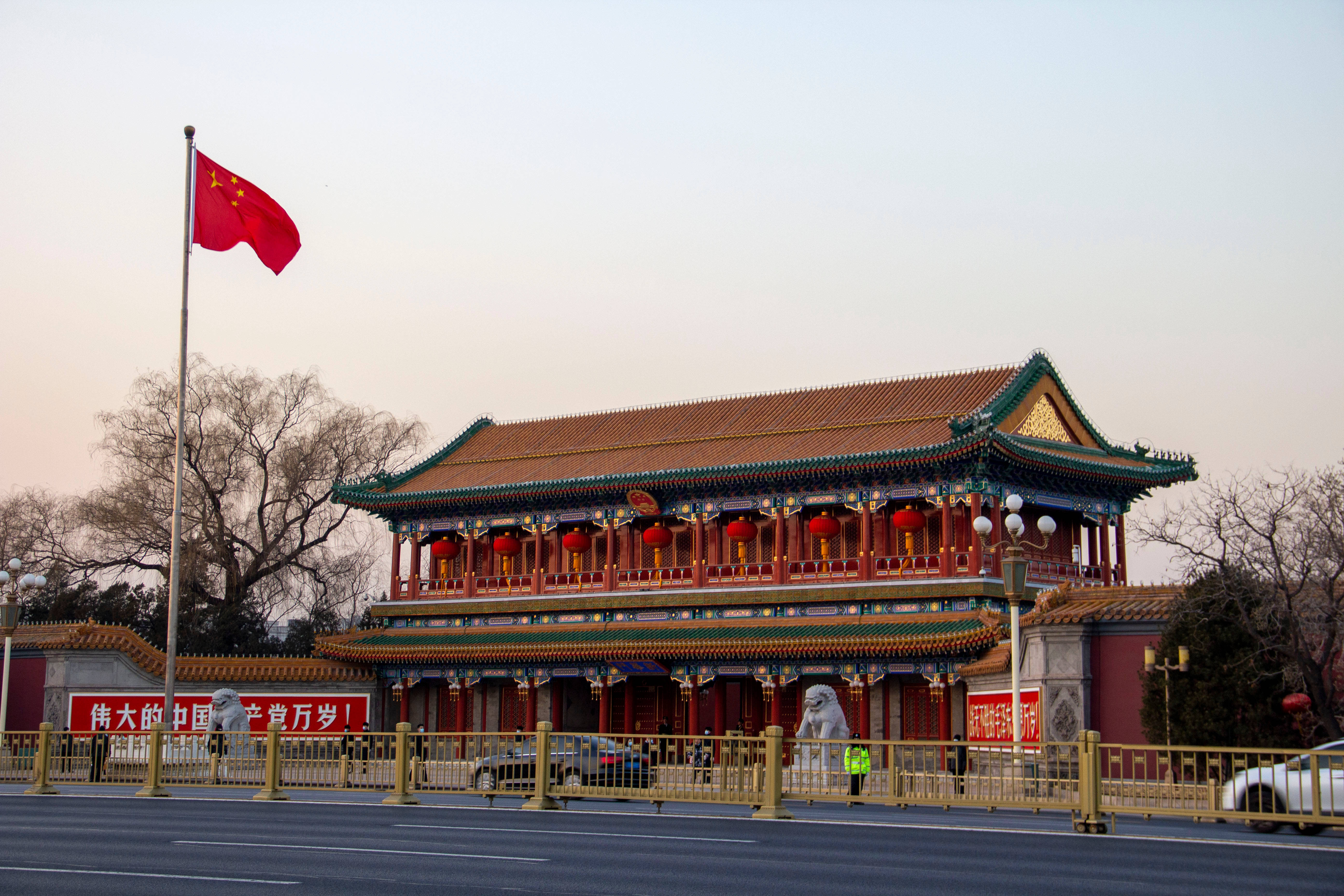 高清 桌布 壁紙 — 宏偉的傳統中國門樓，掛著紅燈籠，中國國旗在淡黃的夕陽天空下飄揚。
