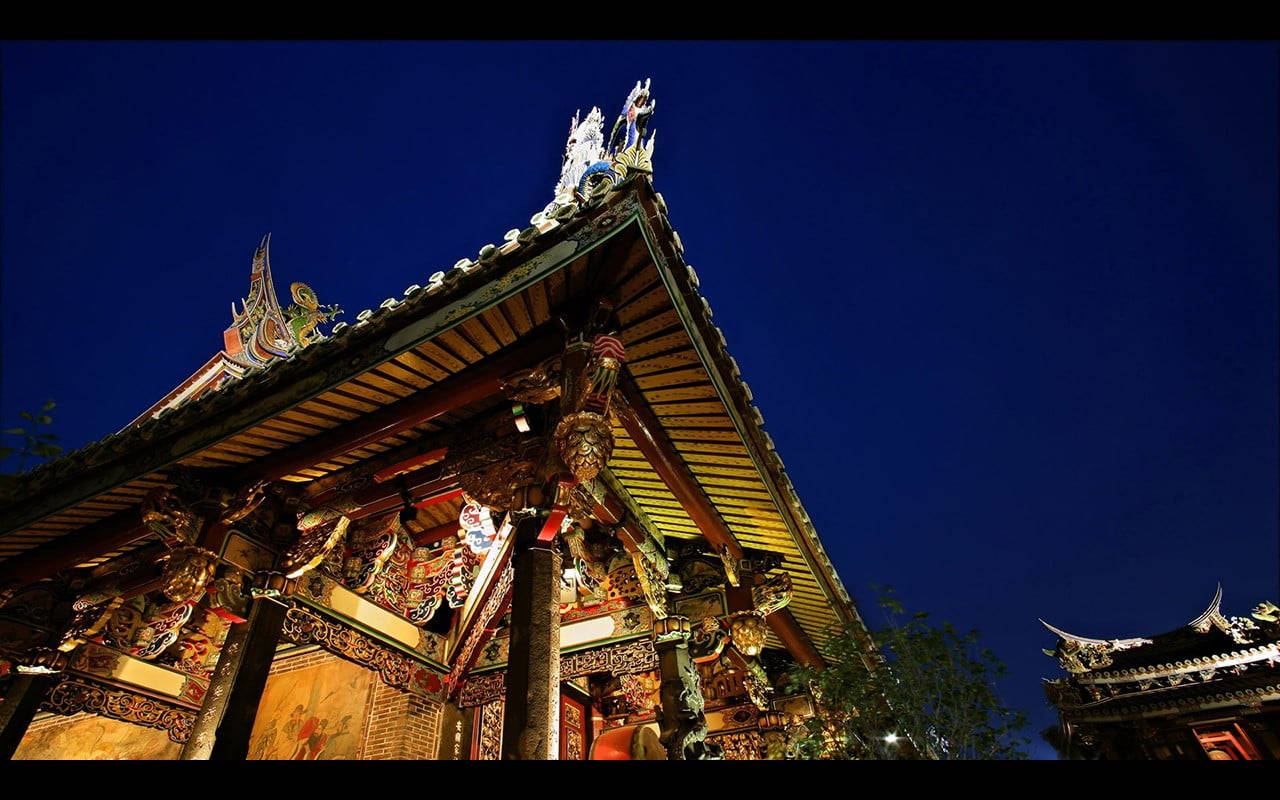 中式房屋壁紙 桌布 壁紙 — 宏偉的傳統寺廟屋頂在深藍色夜空下溫暖地發光，採用戲劇性的低角度照明。