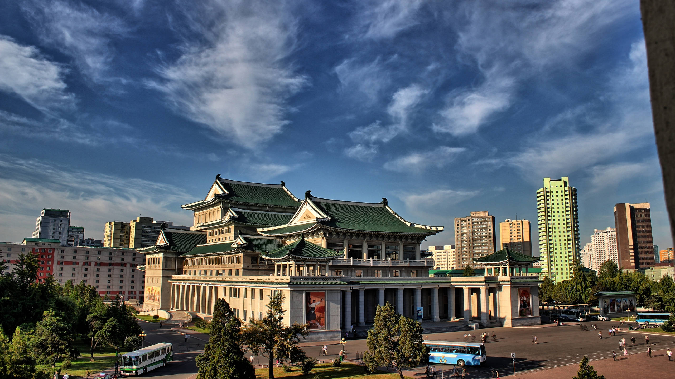 韓國 桌布 壁紙 — 宏偉的傳統建築，綠色屋頂，在都市環境中，戲劇性的藍天下有縷縷白雲。