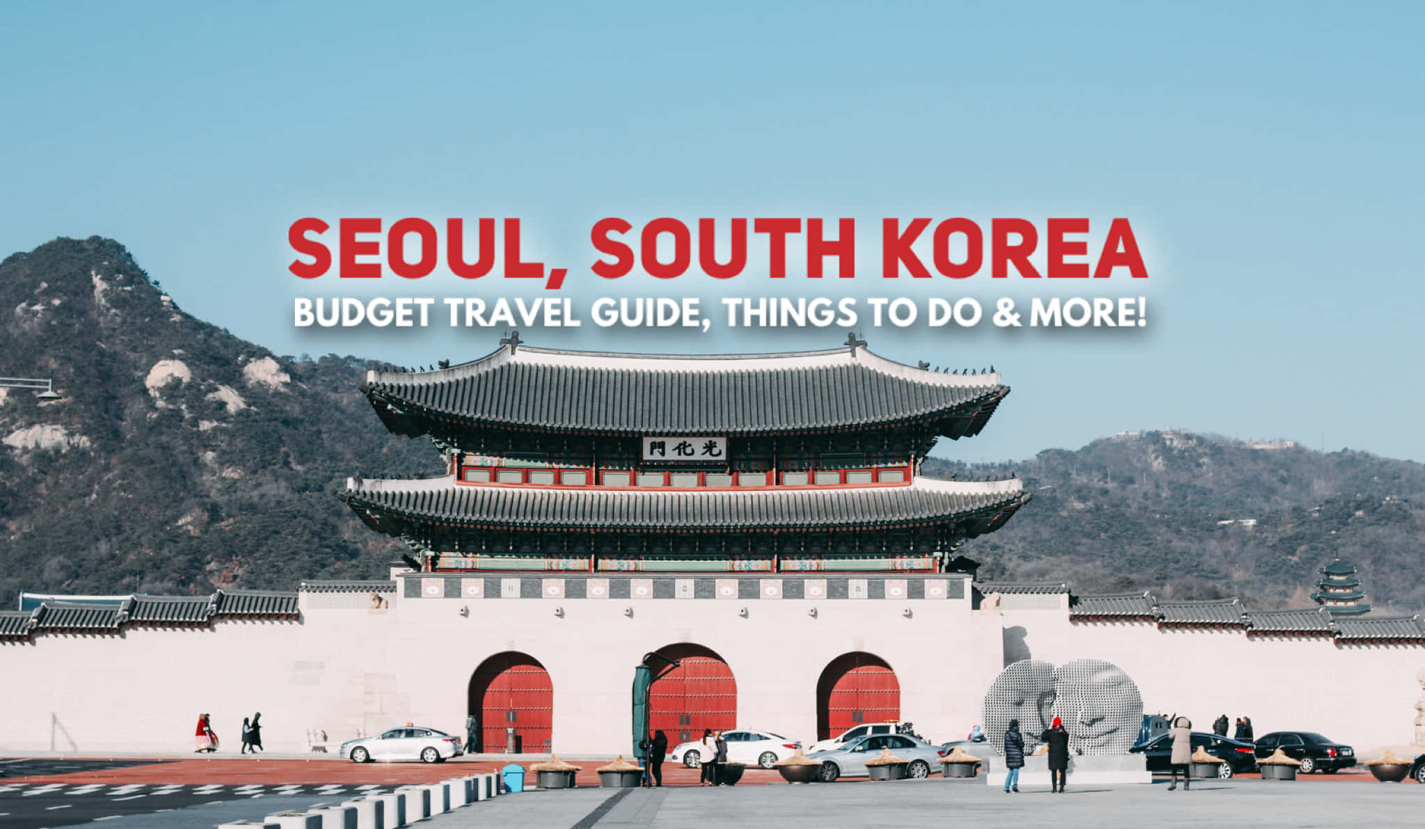 Travel Desktop 桌布 壁紙 — 宏偉的傳統韓國大門，紅色門扉，矗立在青山前，藍天白雲下，附近有遊客和汽車。