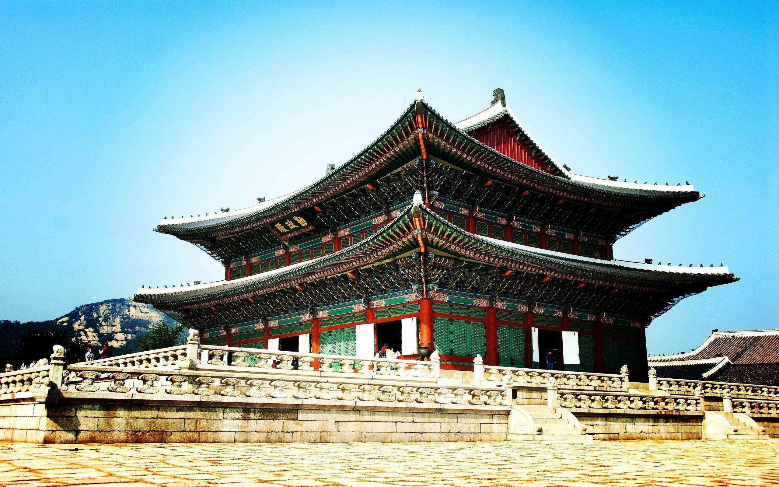 South Korea 桌布 壁紙 — 宏偉的傳統韓國宮殿，擁有寬闊的瓦片屋頂和紅色柱子，在清澈的藍天下。