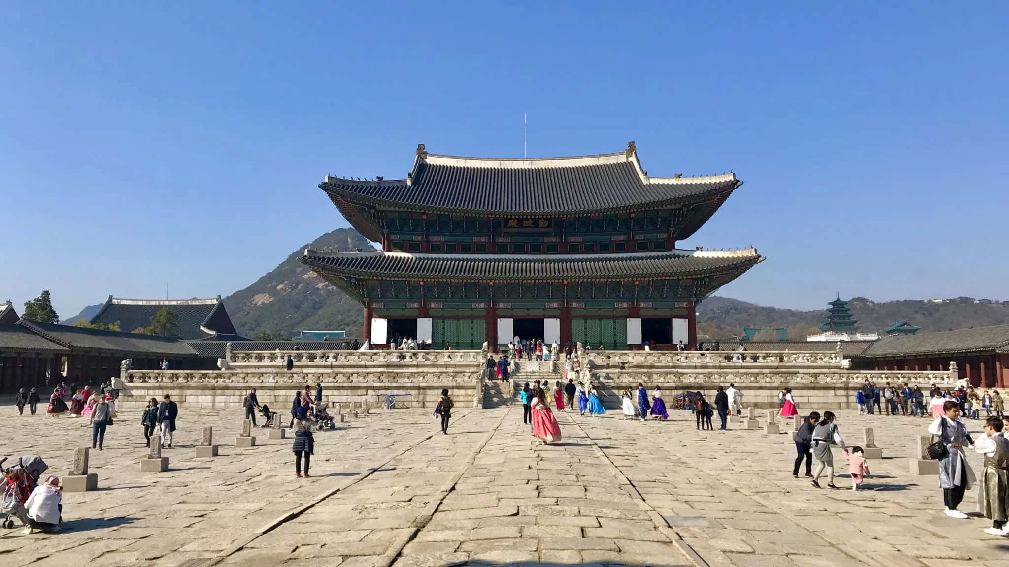 韓國 桌布 壁紙 — 宏偉的傳統韓國宮殿，擁有寬闊的瓦片屋頂和石頭庭院，在清澈的藍天下。