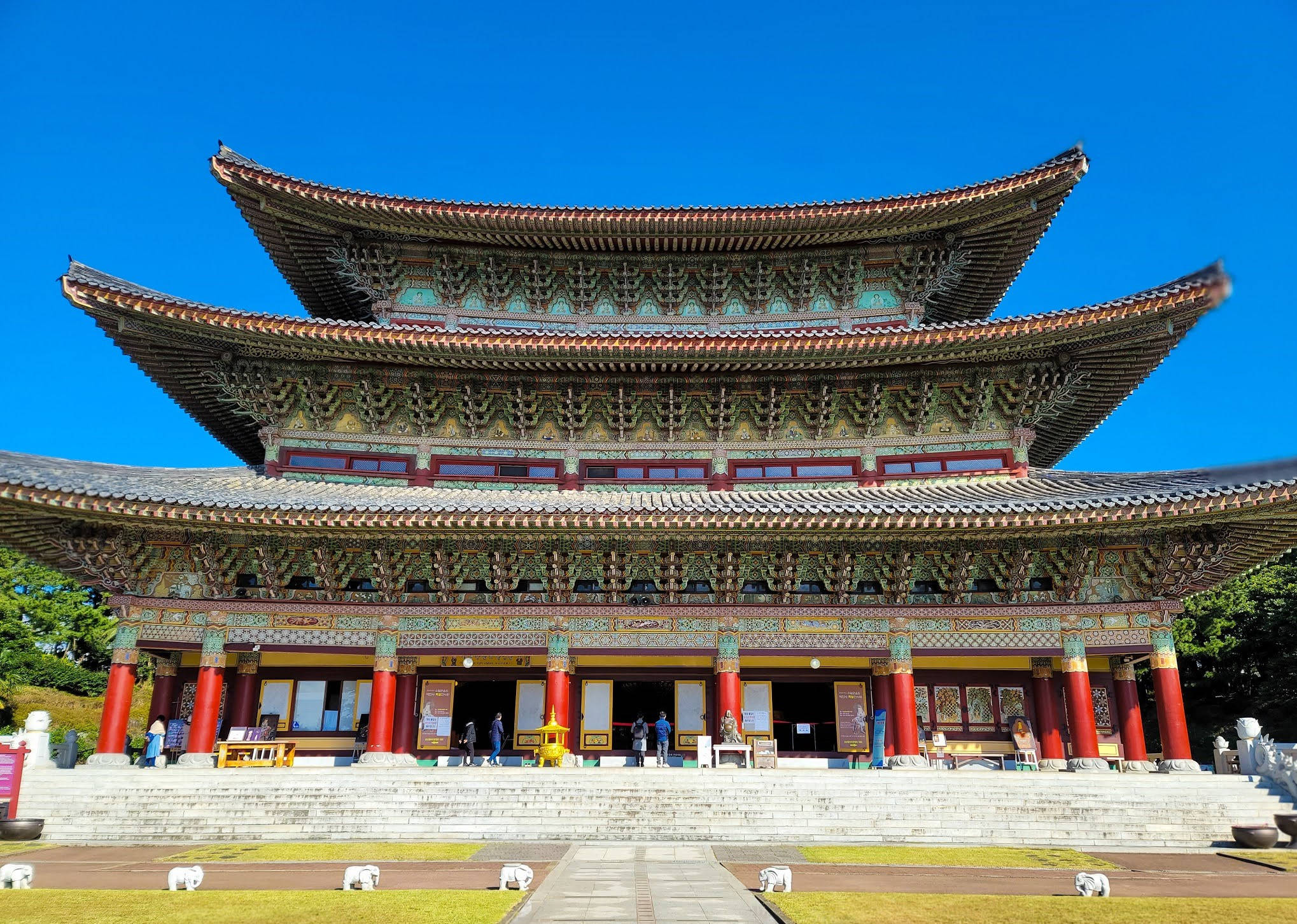 Jeju 桌布 壁紙 — 宏偉的傳統韓國寺廟，擁有分層屋頂和紅色柱子，在清澈的藍天下。