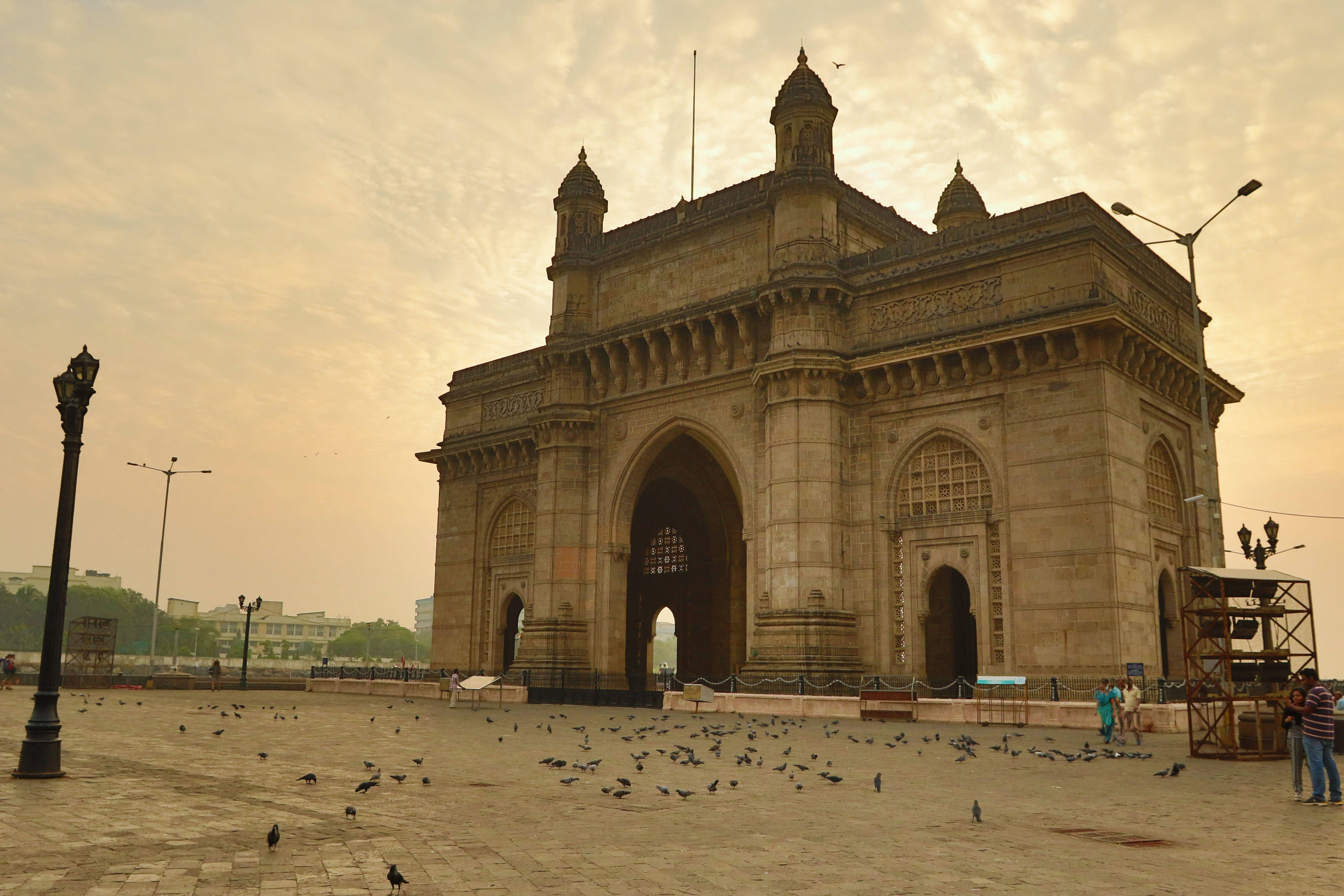Mumbai 桌布 壁紙 — 宏偉的印度之門紀念碑沐浴在金色夕陽中，廣場上散落著鴿子。