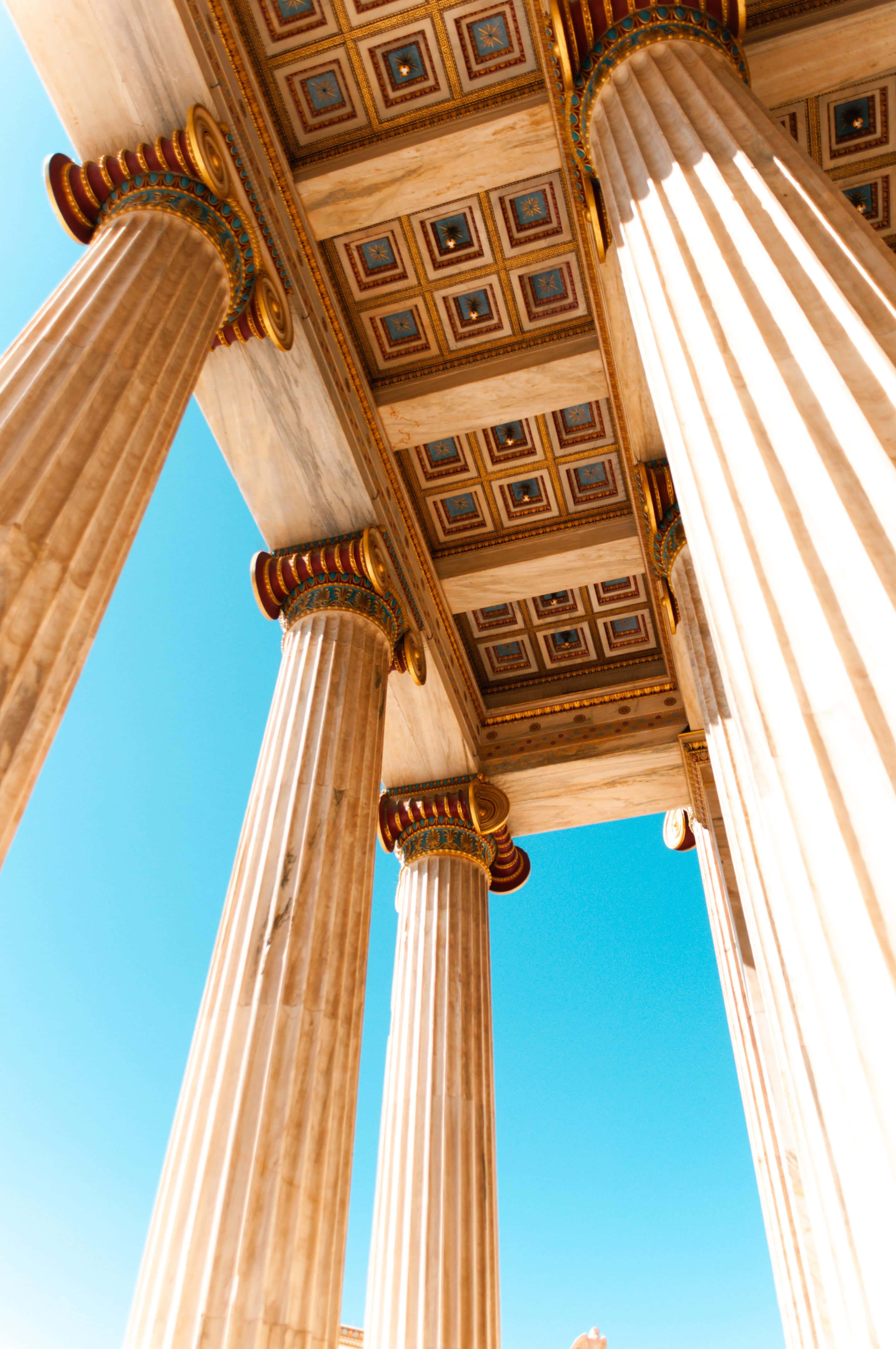 greek 桌布 壁紙 — 宏偉的古老寺廟柱子在戲劇性的低角度拍攝中，向清澈的藍天升起。